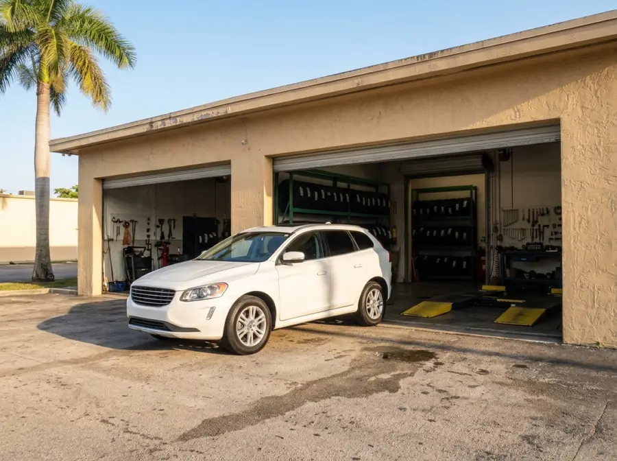 A white SUV pulling into the open bay of a tire and auto shop