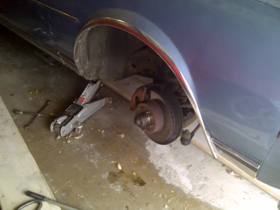 Car on a jack with the wheel off and the brake rotor showing
