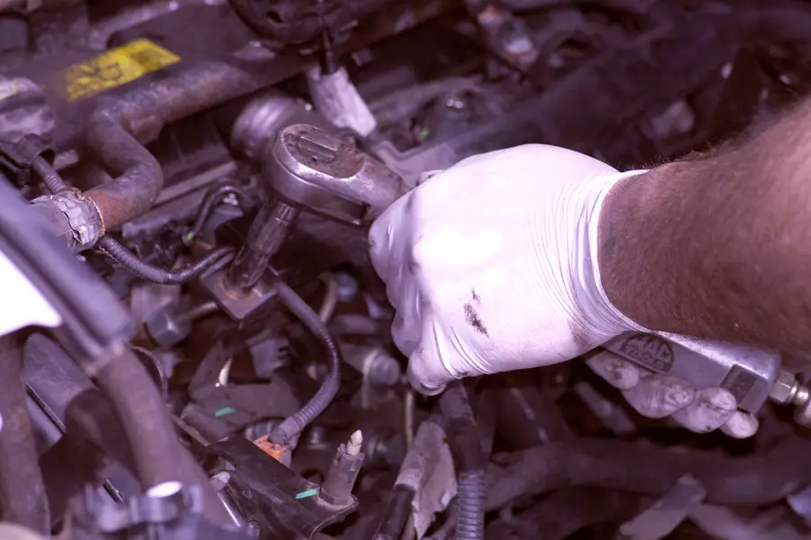 A gloved hand working on a car engine