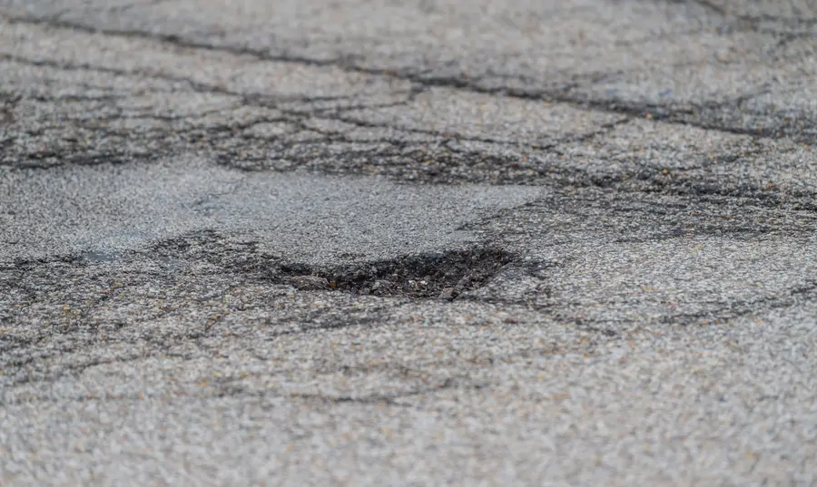 Cracked asphalt and a pothole on a road