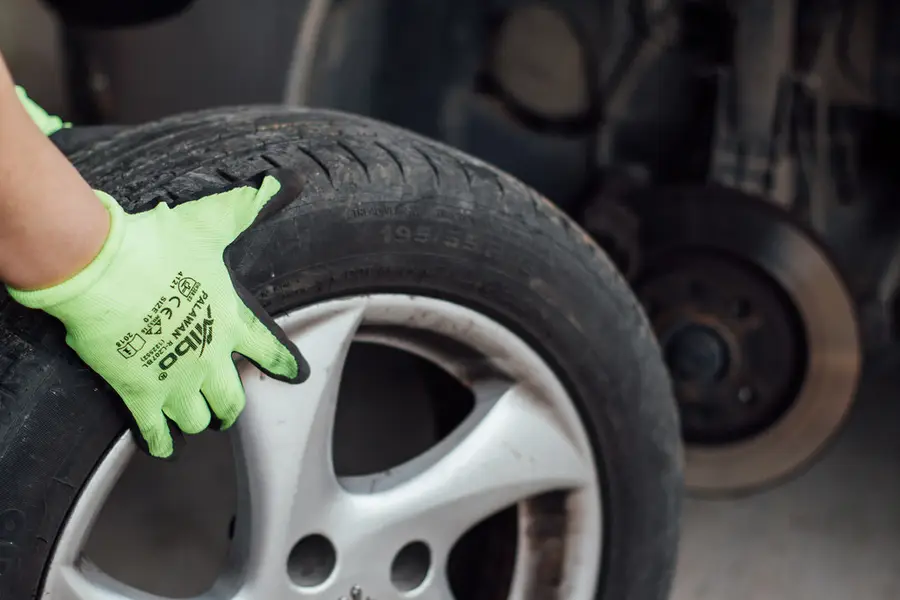 Gloved hand fitting a wheel onto a car's hub